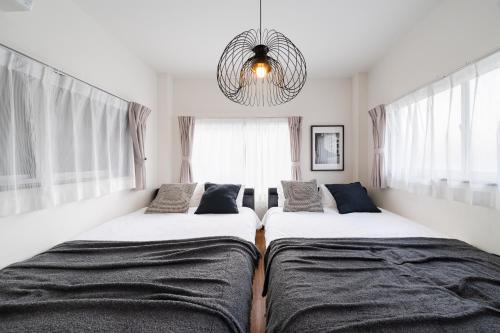 two beds in a room with windows and a chandelier at KOTOBUKI House - Perfect for Groups - 3 Bedrooms, 3 Baths in Tokyo