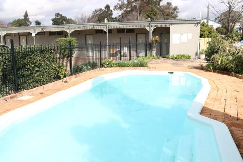 una piscina frente a una casa en Hermitage Motel, en Muswellbrook