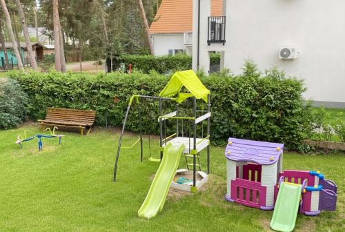 Un parque infantil con un tobogán y una estructura de juego. en Lawendowe Domki i Apartamenty w Pobierowie, en Pobierowo