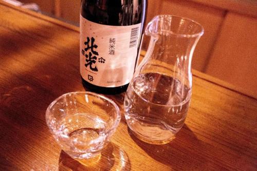 Una botella de vino y una copa en una mesa en Lodge Raven, en Liyama