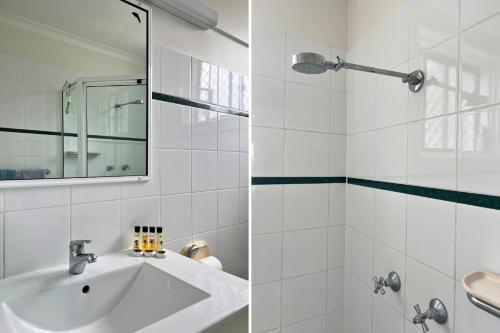 a white bathroom with a sink and a mirror at Surfrider 11 in Mollymook