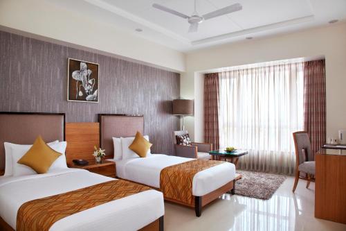 a hotel room with two beds and a desk at Hotel Suba Grand Dahej in Dahej
