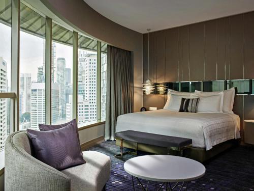 a hotel room with a bed and a chair at Pullman Kuala Lumpur City Centre Hotel & Residences in Kuala Lumpur