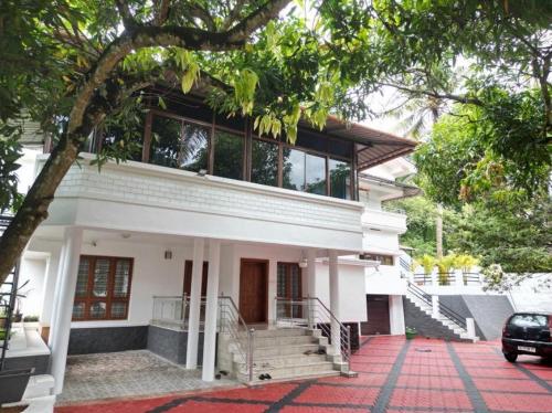 a white house with a staircase in front of it at Altinho Heritage Castle Homestay in Ettumānūr