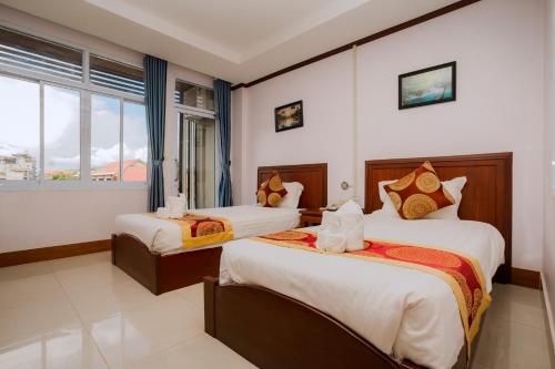a hotel room with two beds and a window at Vilayvong Hotel in Vang Vieng