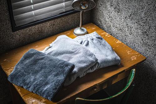 a wooden table with two gray towels on it at The EKAI in Toyohashi