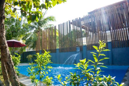 a swimming pool with a fountain in front of a fence at Supreme Dambulla in Dambulla