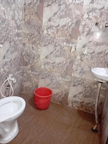 a bathroom with a toilet and a sink and a bucket at Kaushalya Devi Dharamshala in Mathura