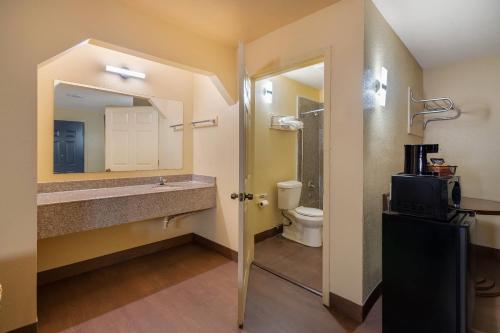 een badkamer met een wastafel, een toilet en een spiegel bij Rodeway Inn & Suites New Orleans East in New Orleans