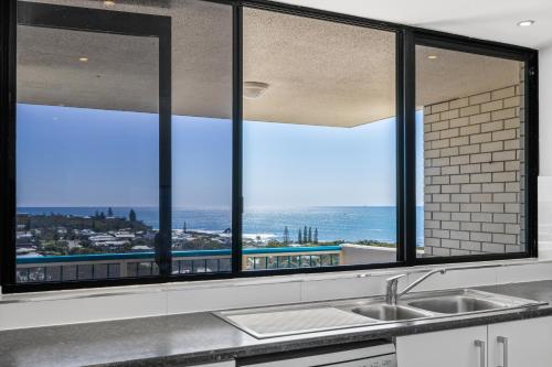 a kitchen with three windows with a view of the ocean at Burgess @ Kings Beach Apartments in Caloundra