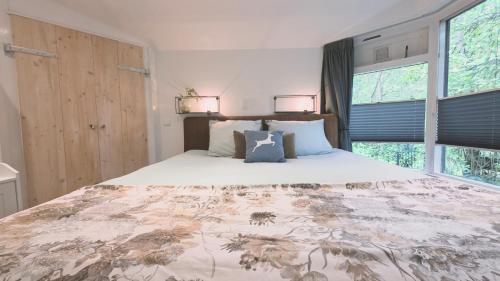 a bedroom with a large bed with two windows at Vliegend Hert, Direct in de Natuur op de Veluwe in Emst