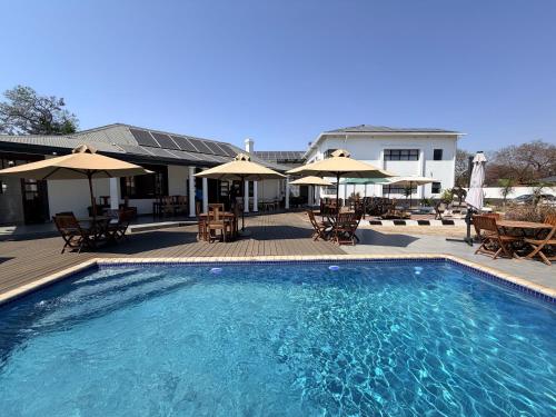 a swimming pool with tables and chairs and umbrellas at 10 on Pauling Hotel Bulawayo in Bulawayo