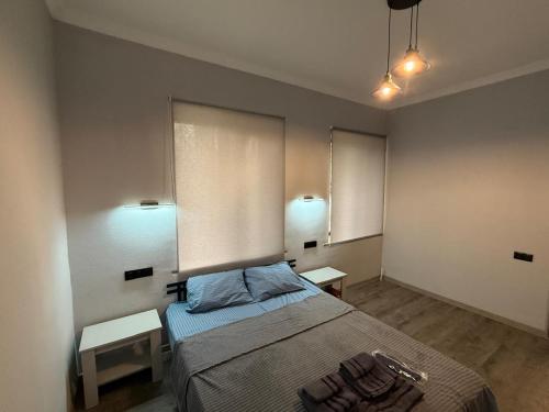 1 dormitorio con 1 cama con 2 mesas y 2 ventanas en Atom Haus, en Tsakhkashen