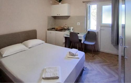 Un dormitorio pequeño con una cama blanca y una cocina. en Amazing Apartment In Janjina With Lake View, en Drače