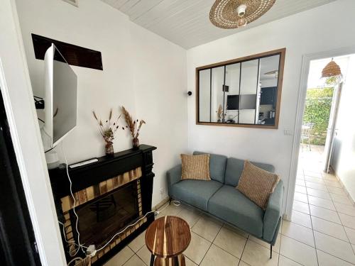 Una sala de estar con un sofá azul y una chimenea. en L'Instant Terrière - Quartier Calme - Proche plage, en La Tranche-sur-Mer