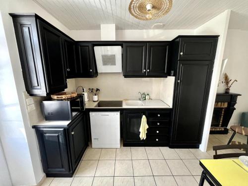 Una cocina con gabinetes negros y un fregadero. en L'Instant Terrière - Quartier Calme - Proche plage, en La Tranche-sur-Mer