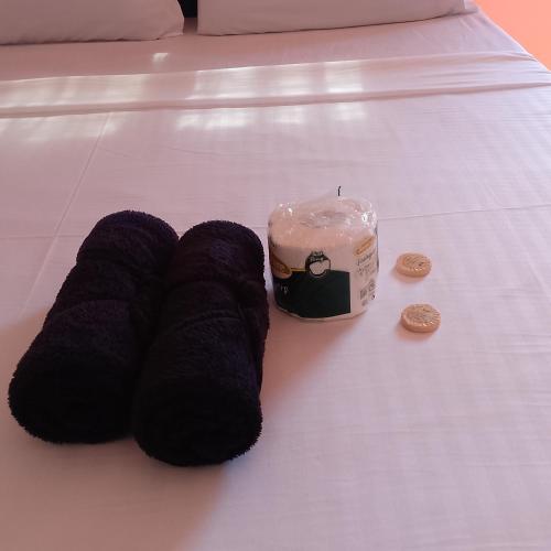 Ein Paar Hausschuhe und eine Kerze auf einem Bett in der Unterkunft Kubo ni klay in San Isidro