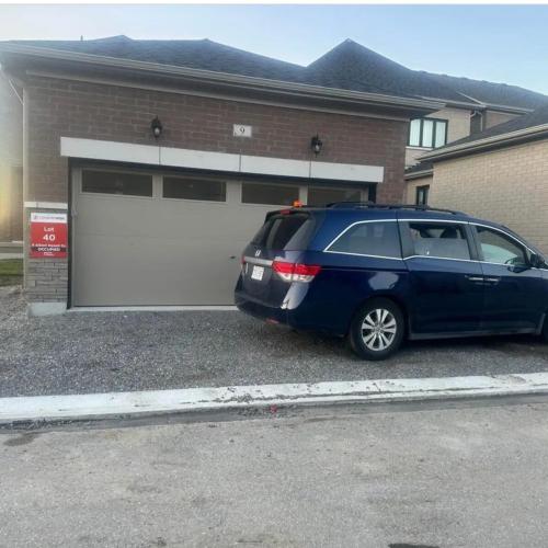 a blue minivan parked in front of a garage at 2 Bedroom private Basement apartment in Markham