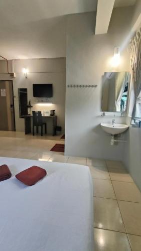 a bedroom with a white bed and a sink at Walk Inn in Miri