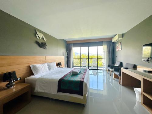 a hotel room with a bed and a desk and a room at The Par Phuket Hotel in Ban Thung Thong