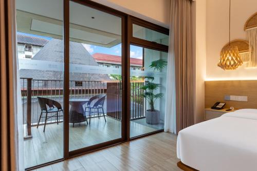 a bedroom with a bed and a balcony with a table and chairs at The Yun Collection Sanya in Sanya