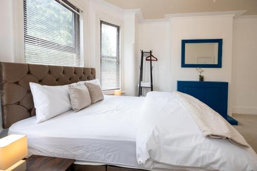 a bedroom with a large bed with white sheets and pillows at Modern 4 Bedroom Victorian Property Private Detached Close to Manchester City in Manchester