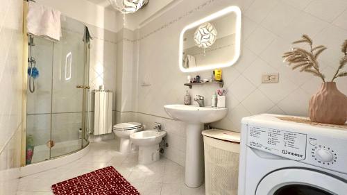 a bathroom with a sink toilet and a washing machine at Trilocale con giardino, posto auto e wi-fi - P034 in Porto Recanati