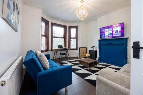 a living room with a blue couch and a tv at Modern 4 Bedroom Victorian Property Private Detached Close to Manchester City in Manchester