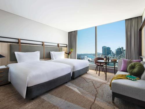 two beds in a hotel room with a view at Sofitel Sydney Darling Harbour in Sydney