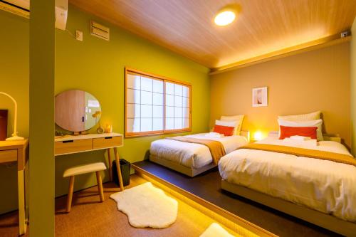 a bedroom with two beds and a sink and a mirror at Tokinoma Furano in Furano