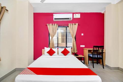 a bedroom with a bed and a red wall at Hotel O Grand Lazeez Dumurjala outdoor Stadium in Sāntrāgāchi