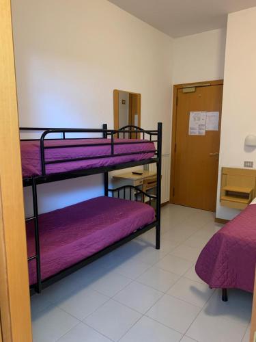 a room with three bunk beds with purple sheets at Hotel Villa Ferrara in Chianciano Terme