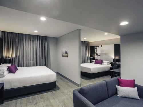 a hotel room with two beds and a couch at Mercure Tamworth in Tamworth