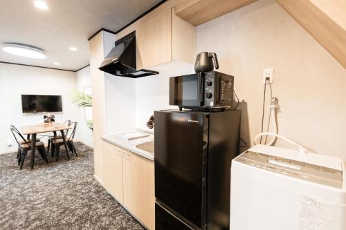 a kitchen with a black refrigerator and a table at b&黒門1号店 in Osaka