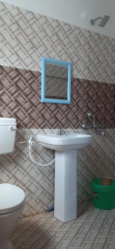 a bathroom with a sink and a toilet and a mirror at Peace Abode Vista in Dibrugarh
