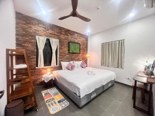 a bedroom with a bed and a brick wall at Betel Hoi An Homestay in Cam Thanh