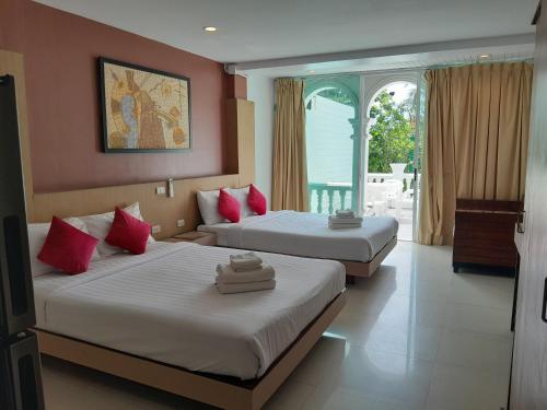 Una habitación de hotel con dos camas y una ventana. en Island Patongbeach Apartments, en Patong Beach