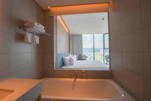 a bathroom with a tub with a view of a bedroom at Anstay Residence by A La Carte Hạ Long in Ha Long