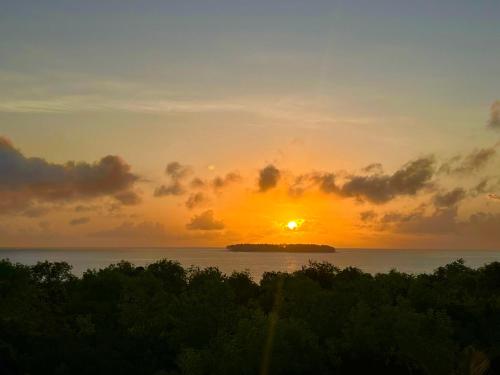 a sunset over the ocean with a small island in the water at Alcyone Residence - Ocean View Villa in Muyuni