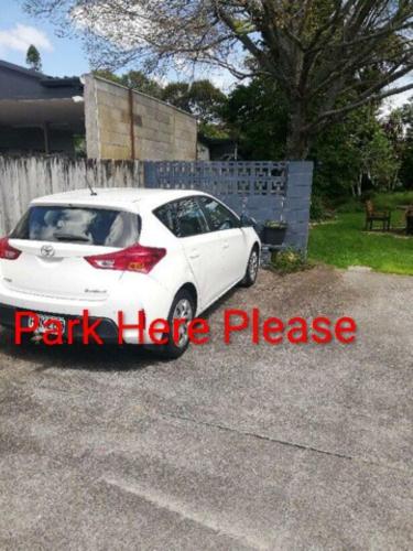 a white car parked in the driveway of a house at Songbird Sleepout with bathroom and mini kitchenette in Hamilton