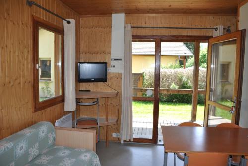 a living room with a couch and a television and a table at Camping du Haut-Koenigsbourg - Onlycamp in Lièpvre