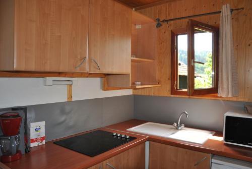 a kitchen with wooden cabinets and a sink and a window at Camping du Haut-Koenigsbourg - Onlycamp in Lièpvre