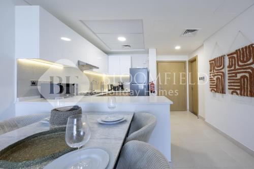 MushayribにあるBloomfields Iconic 2 Br Radiant Boulevard Reemのダイニングルーム(テーブル、ワイングラス2杯付)