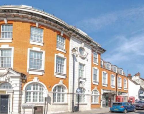 a large brick building with a car parked in front of it at Charming 1 Bedroom Flat in the Heart of Uxbridge in Uxbridge