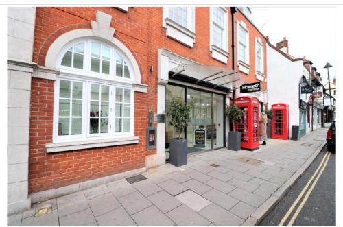 a brick building with two red phone booths on a street at Charming 1 Bedroom Flat in the Heart of Uxbridge in Uxbridge