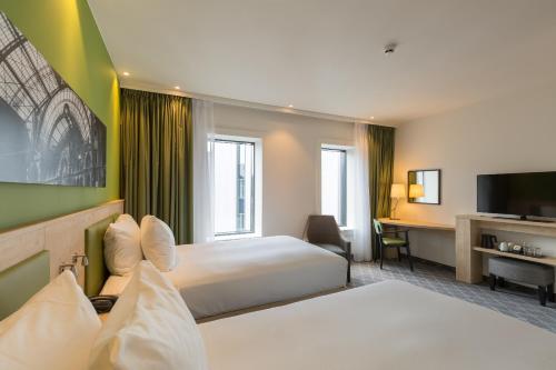 a hotel room with two beds and a desk at Hampton By Hilton Antwerp Central Station in Antwerp