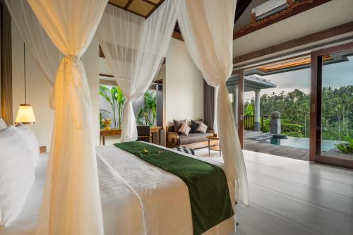 a bedroom with a bed and a living room at Sanggraloka Ubud in Ubud