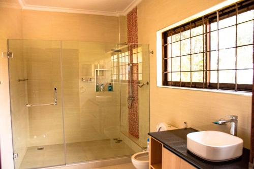 a bathroom with a shower and a toilet and a sink at Ekom Nest in Musereita