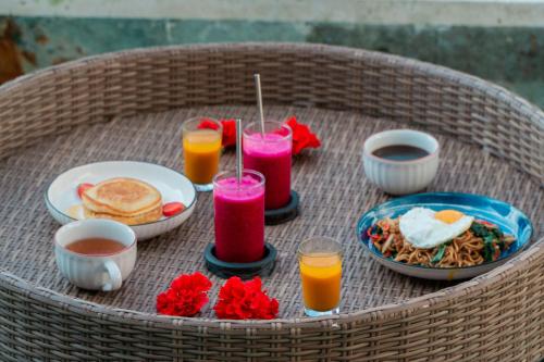 Una mesa con alimentos para el desayuno y dos vasos de jugo. en The Alvarendra Ubud Villa By Bali Cabin, en Ubud