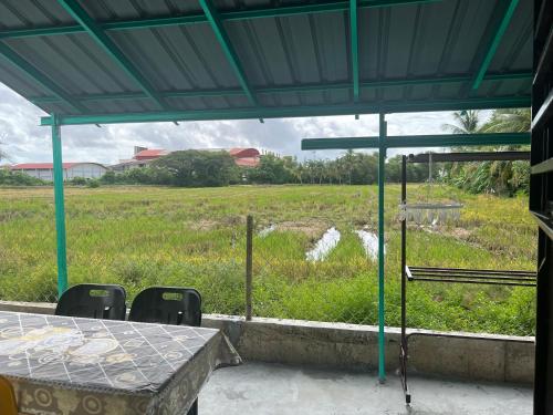 a table and chairs with a view of a field at Homestay Teratak Ainaz in Alor Setar